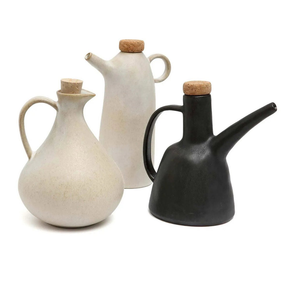 Three ceramic oil bottles in white, black, and beige on a white background