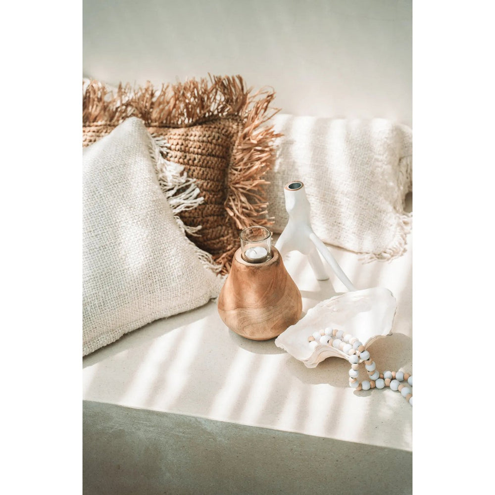 Decorative setting with a wooden vase, white pillow, and decorative plant on a neutral background