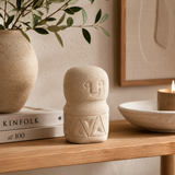 Decorative stone figure on a wooden surface with books and a candle in the background